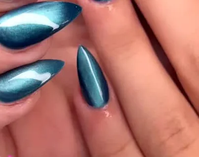 Ongles stiletto bleu canard à effet cat-eye, la bande de lumière traverse chaque ongle.