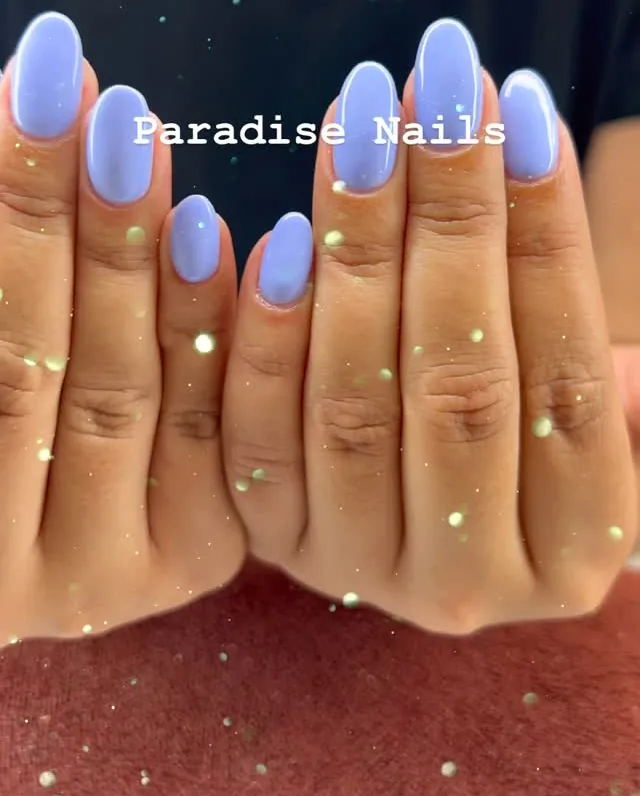 Ongles amande lavande brillants, deux mains jointes sur un fond pailleté.